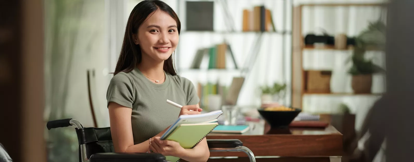 A woman seated at a desk holding a notepad
