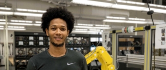 student standing around an industrial robotic arm