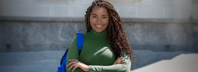 A woman wearing a green shirt with a backpack slung over one shoulder